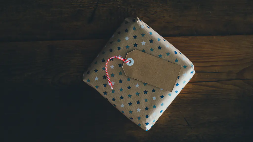 A small wrapped gift with a blank paper tag on a dark wooden table