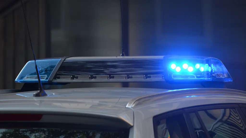 Blue emergency light bar flashing on the roof of a silver car at dusk