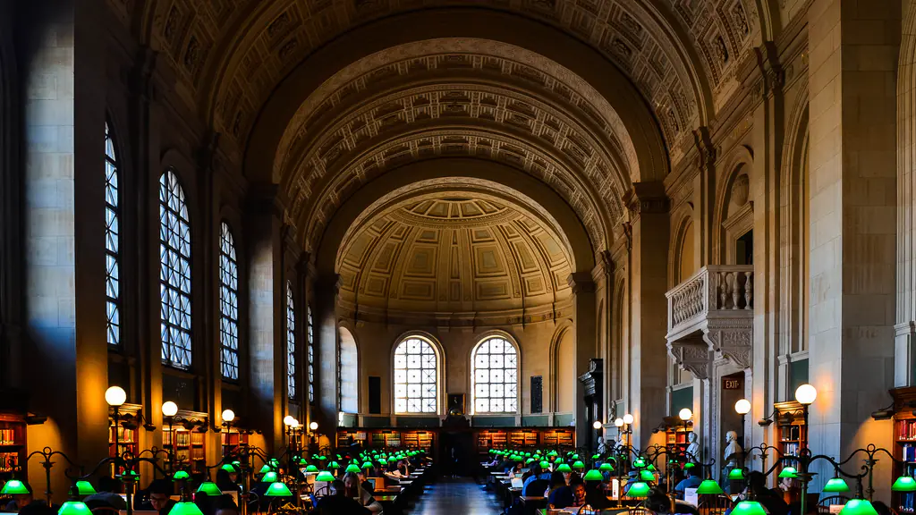 The vaulted Bates Hall reading room of the Boston Public Library, its long tables lit by green lamps